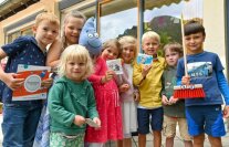mehrere Kinder halten einen Besen und Karten in der Hand